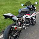 Motorcycle parked on a road near a grassy area with a lake in the background