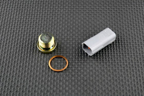Yamaha FJR 1300 O2 sensor eliminator kit components: cap, connection, and copper washer on textured surface.